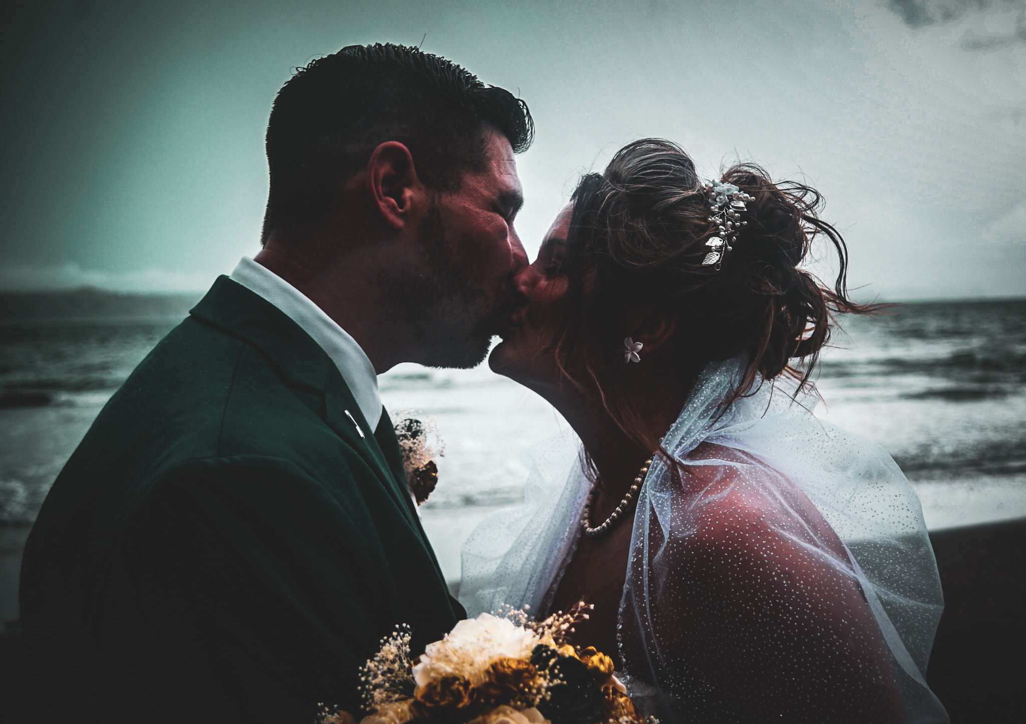 Newlyweds kissing beside the ocean