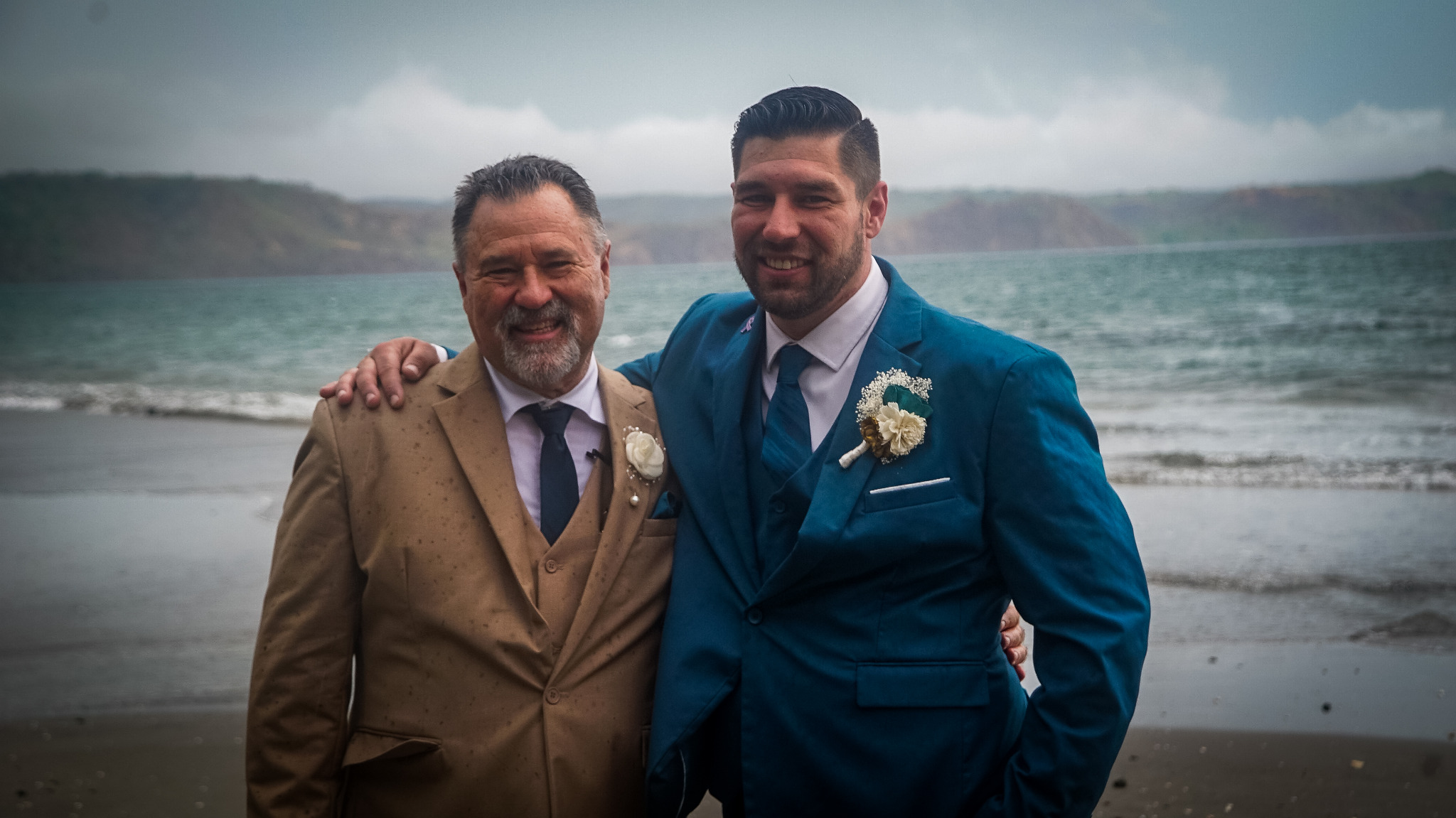 Groom posing with a family member on the beach